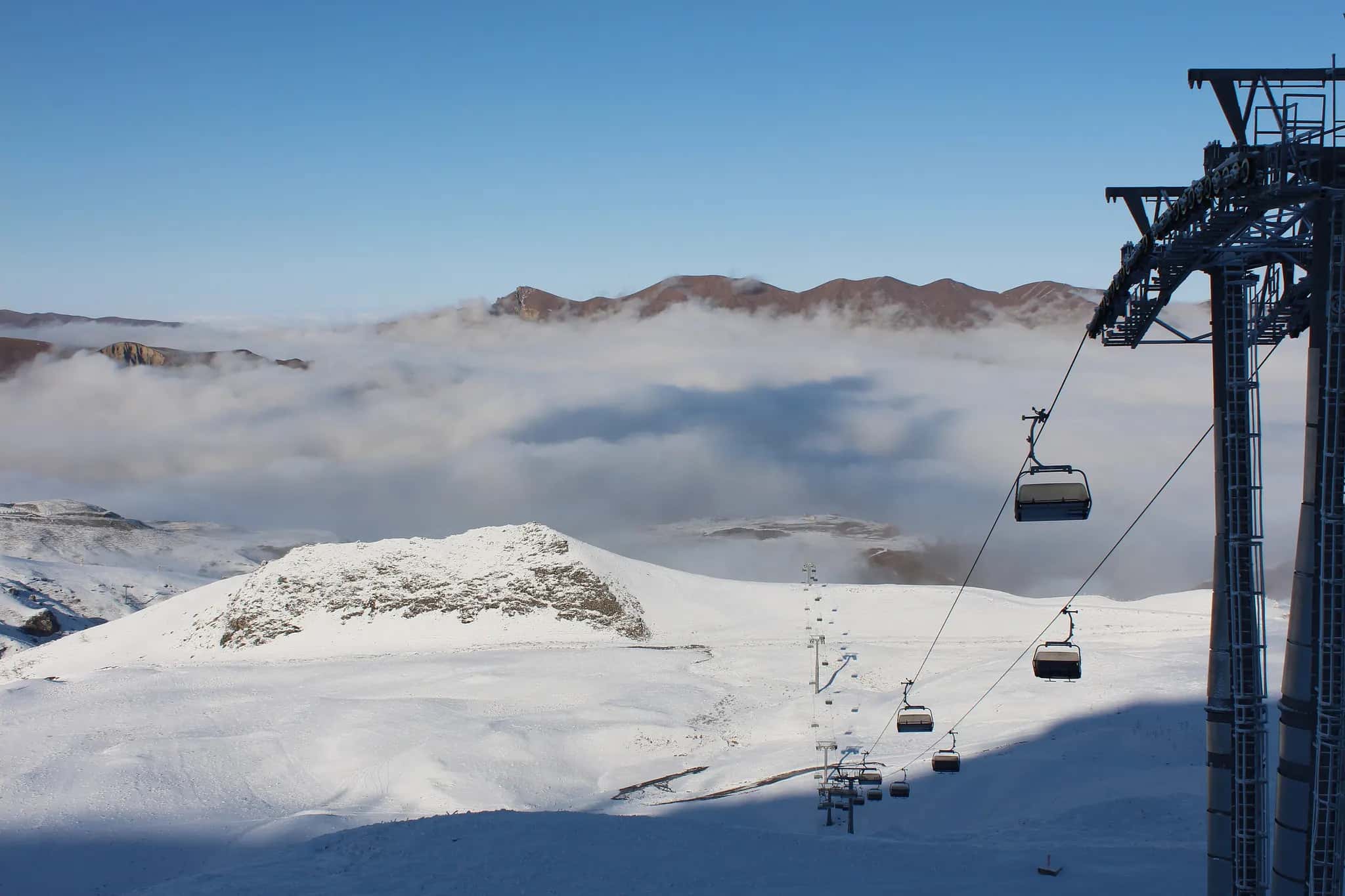 Cable car crossing above the clouds over the snowy slopes of Shahdag
